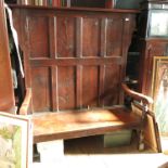 An antique style high back settle, having eight fielded panels and a solid seat, maximum depth