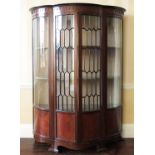 An Edwardian mahogany display cabinet, of ogee form, with glazed and panelled doors, below a