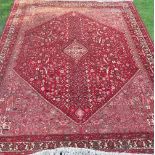 An Eastern style rug, the red ground decorated with repeating symbols, 120ins x 82ins