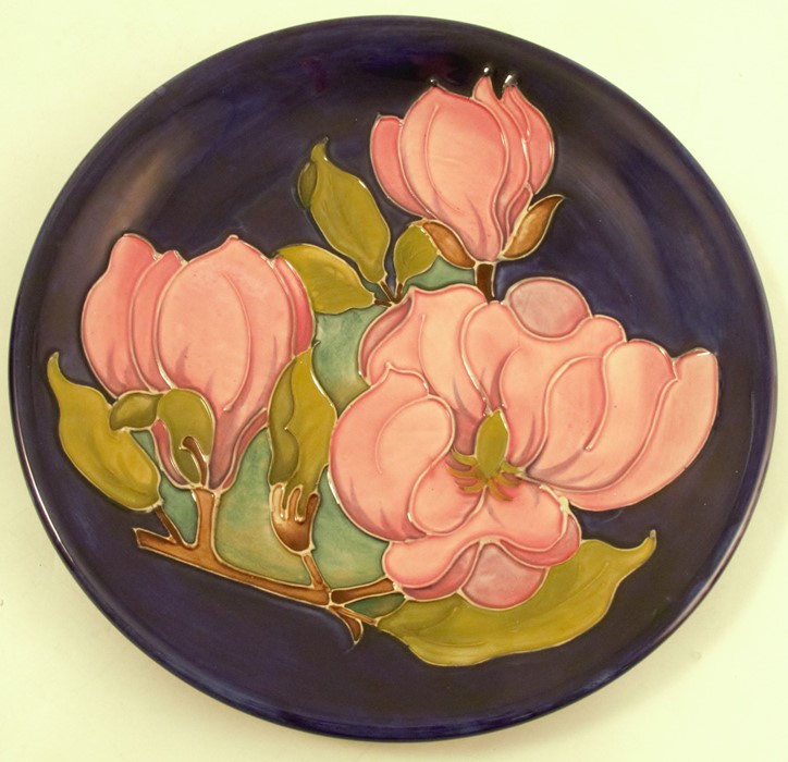 A Moorcroft Pottery plate, decorated in the Magnolia patter, to a blue ground, diameter 10.