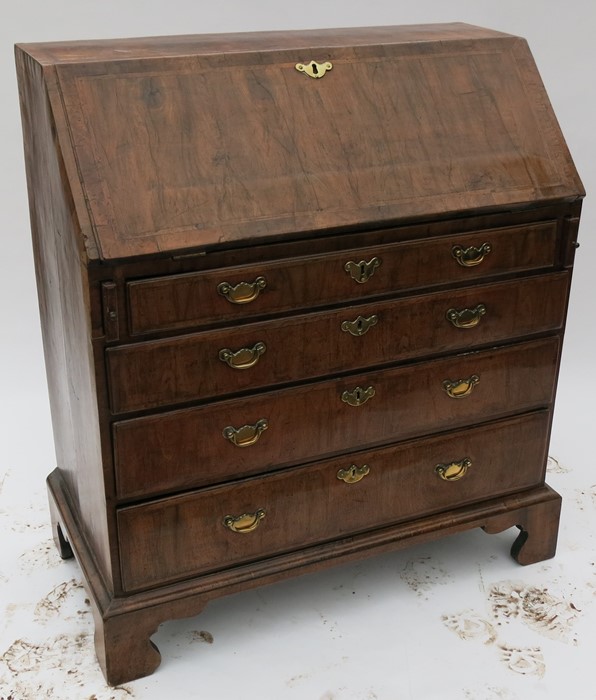 A Georgian walnut bureau, the sloping fall flap opening to reveal pigeonholes and drawers, over four