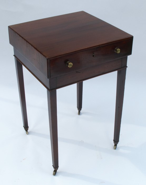A late Georgian mahogany free standing lamp table, having an overhanging top and single drawer,