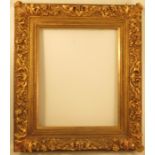 A gilt wood and composition picture frame, with flower and scroll decoration, the slip with name and