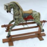 An Edwardian rocking horse, painted in dapple grey, with saddle and bridle, on a beech wood base,