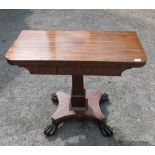 A 19th century rosewood fold over card table, raised on a turned column, on a base with claw feet,