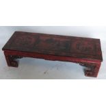 An oriental red lacquered low table, of rectangular form, decorated with flowers, birds and a