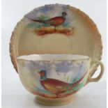 A Locke & Co Worcester blush ivory tea cup and saucer, decorated with a cock pheasant by J