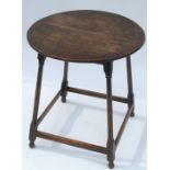 A circular oak occasional table, raised on four turned legs, united by a stretch, diameter 21ins,