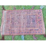 An Eastern saddle bag rug, decorated in red and blue to a brown ground, 41ins x 26ins