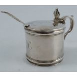 A silver mustard pot, of cylindrical form, the hinged lid engraved with a crest and the body with an