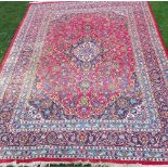 A modern Eastern style rug, decorated with flowers to a red ground field, 117ins x 76ins