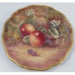 A Royal Worcester plate, decorated with fruit to a mossy background by J Skerrett, with gilt