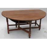 An antique yew wood gate leg dining table, of near circular form, raised on turned legs, 63.5ins x