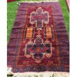 An Eastern style rug, with burgundy ground field and blue ground borders, decorated in repeating