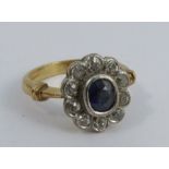 A sapphire and diamond 18 carat gold cluster ring, the oval cut enclosed by ten old brilliant cut