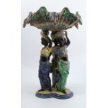 A 19th century majolica centre piece, the shaped bowl supported on three figures, to a triform base,