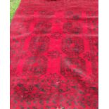 An Eastern style rug, the red ground decorated with repeating motifs, 82ins x 55ins