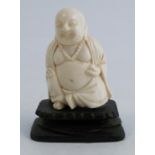 A carved ivory model, of a seated Buddha, on a carved wooden base, height including base 2.75ins