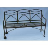 A Regency wrought iron garden bench, with curved back, the one end on wheels, height 38.5ins,