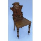 A 19th century oak hall chair, with shield shaped carved back, solid seat, raised on turned front