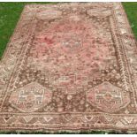 A Shiraz wool rug, decorated in reds and browns with repeating symbols and animals, 101ins x 68ins