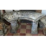 A stone garden bench, of curved form, raised on supports, width 36ins, height 19ins