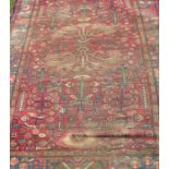 An Eastern style rug, the red ground field decorated with styalised flowers and trees, 80ins x 52ins