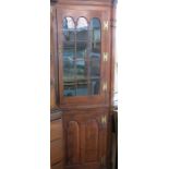 A 19th century yew wood floor standing corner cupboard, with glazed upper door and double fielded