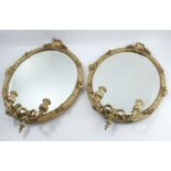 A pair of 19th century gilt framed wall mirrors, with oval bevelled plate, the frame decorated