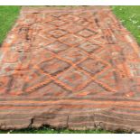 A Kelim rug, decorated in orange, brown, black and grey with repeating symbols, 131ins x 72ins