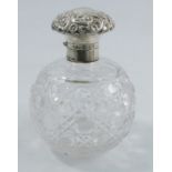 A glass dressing table bottle, with hinged silver top, the top embossed with flowers and scrolls and