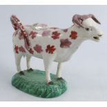 A 19th century Swansea cow creamer, the iron red dabble body and raised on a green base, height 5.