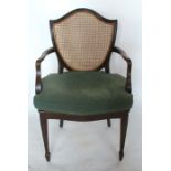 A 19th century mahogany open arm chair, with shield shaped cane back and cane seat