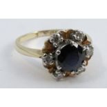 A sapphire and diamond 18 carat gold cluster ring, the round cut stone enclose by six single cut
