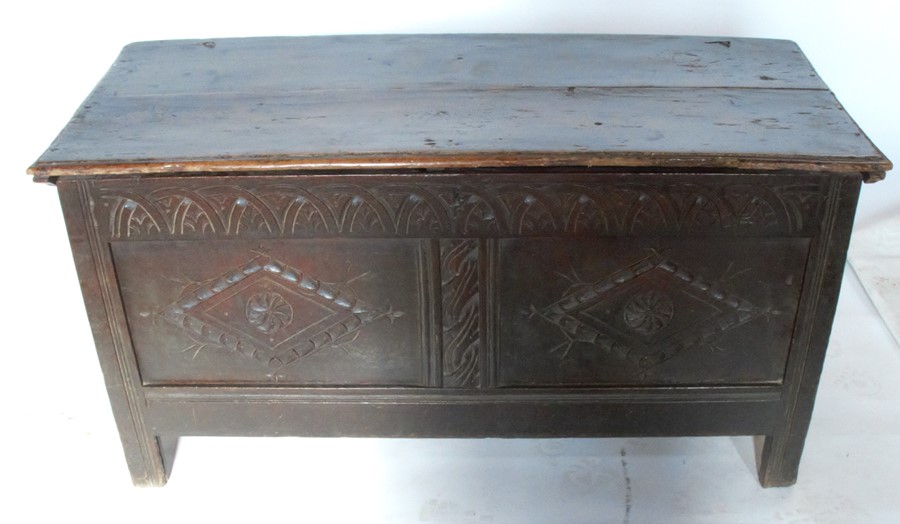 An Antique oak coffer, with twin carved panels to the front, depth 21ins, width 48ins, height 25ins