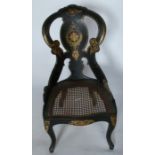A Victorian black papier mache chair, with gilt decoration to the black ground, having a cane