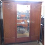 An Edwardian mahogany triple door wardrobe, having a mirror door and two doors inlaid with mother of