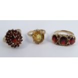 A 9 carat gold garnet cluster ring, together with a three stone garnet ring, and a yellow stone