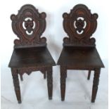 A pair of 19th century hall chairs, the shield shaped back carved with a mask, having solid seats