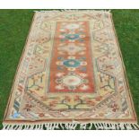 An Eastern design rug, decorated with triangular lozenges and flowers to an orange ground, 47ins x