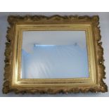 A gilt framed wall mirror, of rectangular form, the frame decorated with scrolls, fluting and