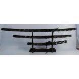 Three modern Samurai swords, with carved black scabbards and metal mounts, length 39ins, together