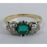 A diamond and emerald three stone ring, the yellow mount unmarked, the octagonal emerald