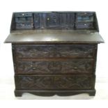 An Antique dark oak carved bureau, the fall flap opening to reveal drawers, cupboard and pigeon