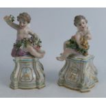 A pair of 19th century porcelain figures, of cherubs seated on plinths, one with flowers the other