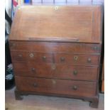 An Antique oak bureau, the fall flap opening to reveal a well, pigeon holes and drawers, with two