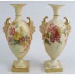 A pair of Royal Worcester blush ivory vases, decorated with floral sprays, with mask handles, raised