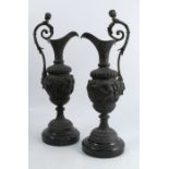 A pair of 19th century cast metal ewers, in the Classical style with embossed decoration of putti