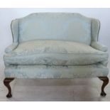 A Queen Anne Style upholstered settee, with shaped back, wing sides and raised on mahogany