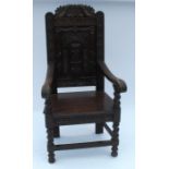 An Antique oak carved arm chair, the back with shaped top and carved with a vase on a pedestal